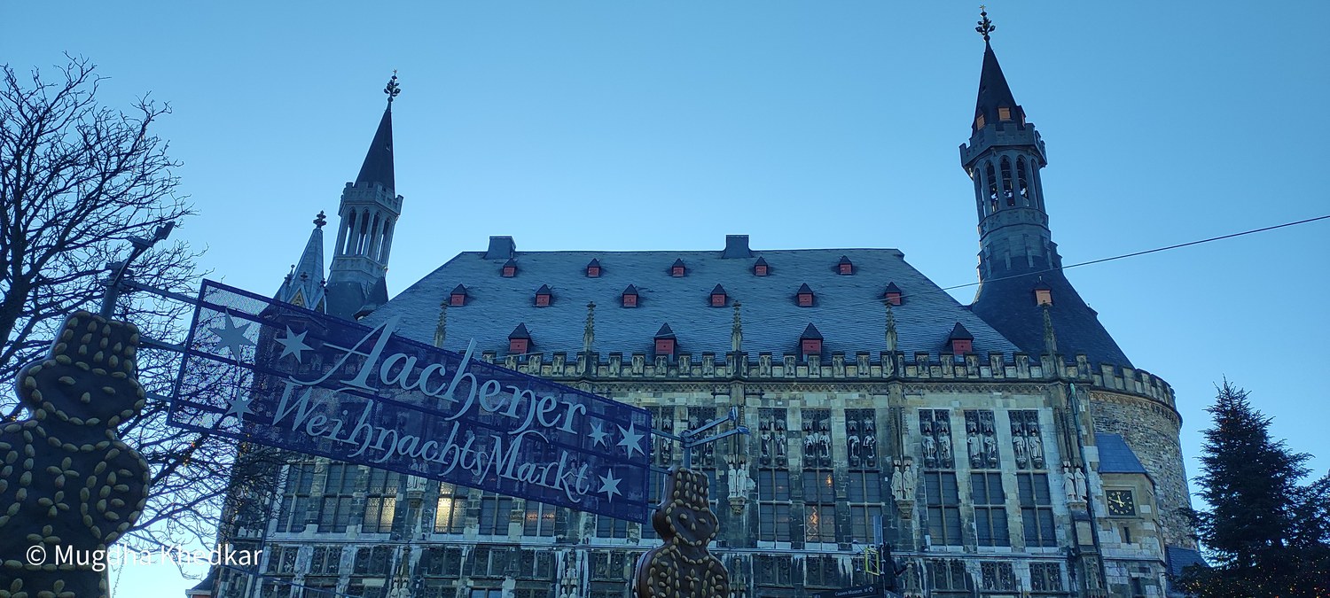 Aachen City Hall at dusk behind the Christmas market sign