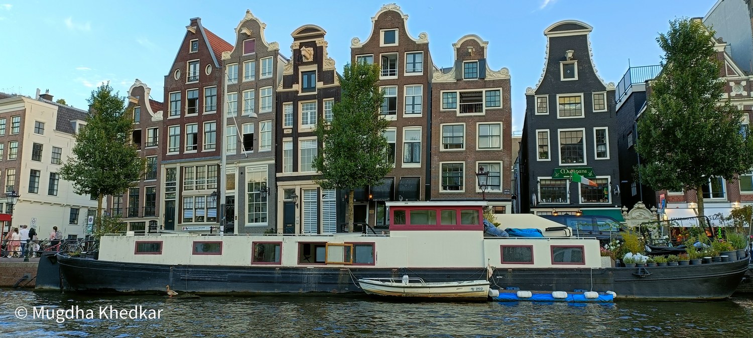 Narrow gabled canal houses and a houseboat in Amsterdam