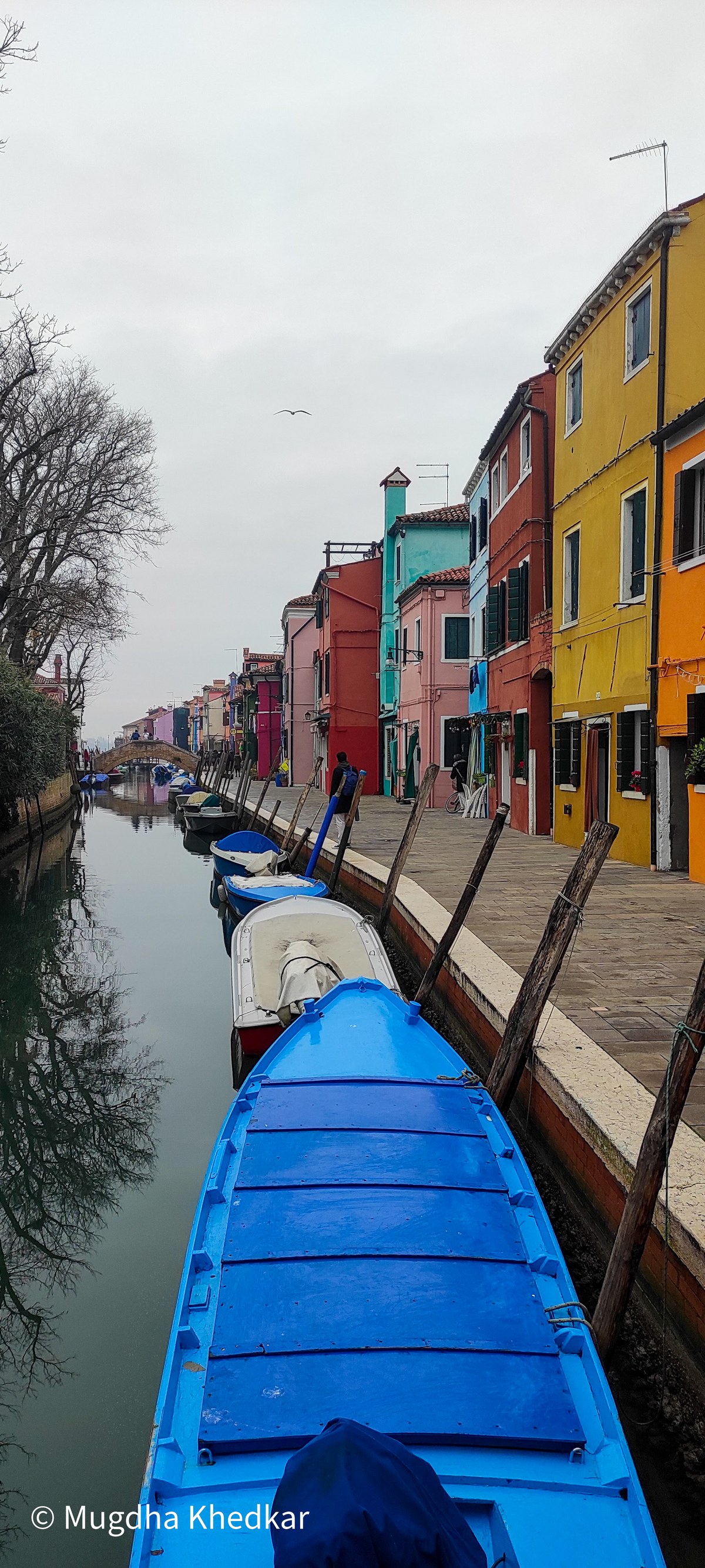 Brightly painted houses and a blue boat along a canal in Burano