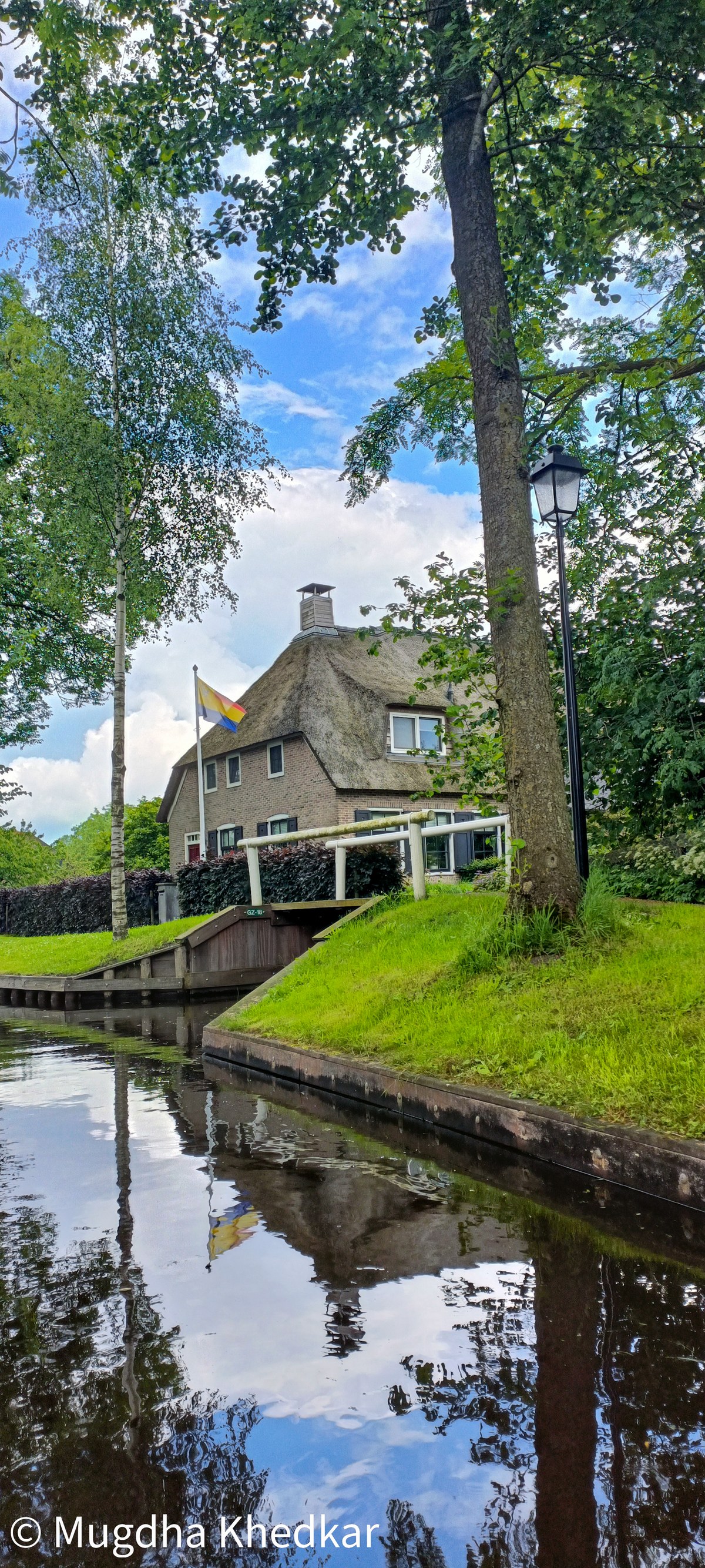 A thatched-roof house and footbridge reflected in a canal in Giethoorn