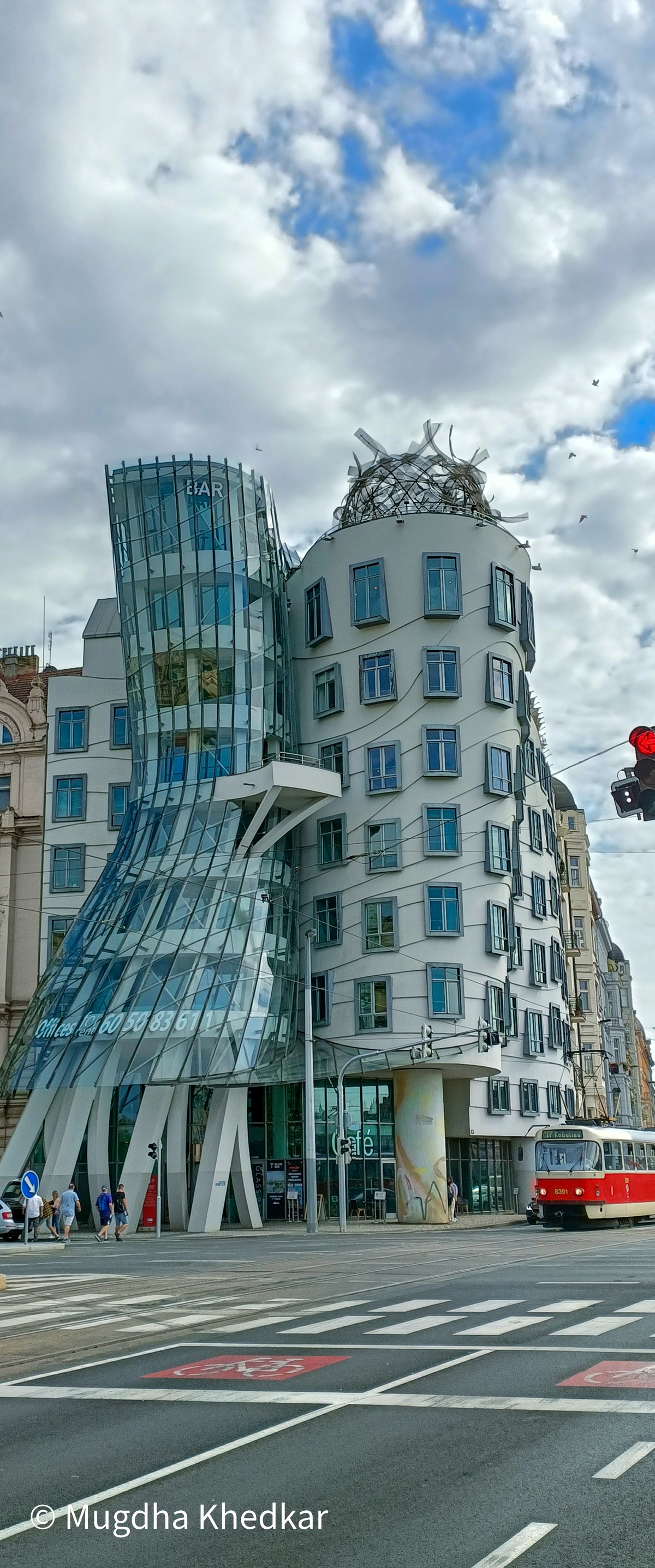 The Dancing House in Prague with a red tram passing by