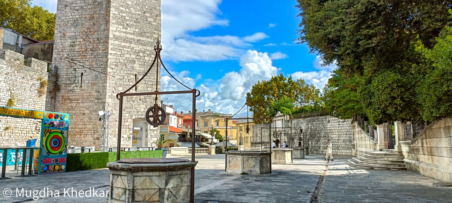 A stone wellhead and a medieval tower in Zadar's old town